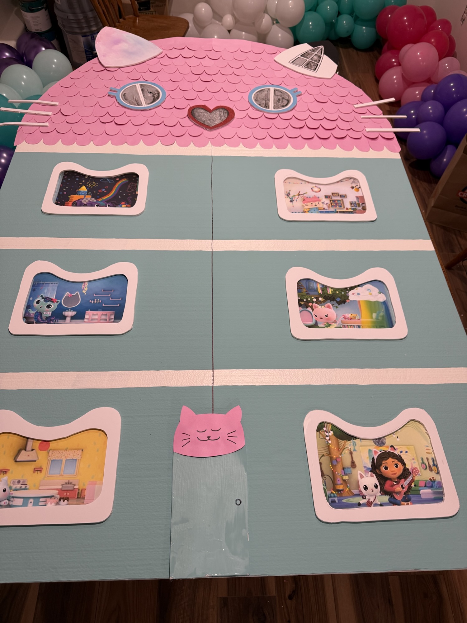 DIY Gabby's dollhouse foam backdrop with handmade character windows for a Gabby's Dollhouse-themed birthday party.