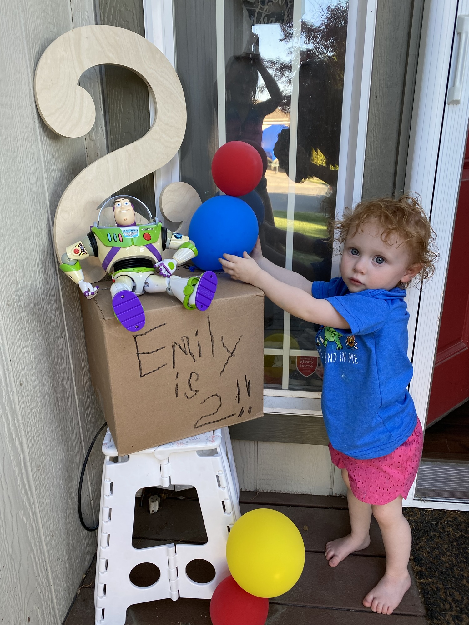Toddler playing beside birthday party decorations and a homemade Buzz Lightyear party display.
