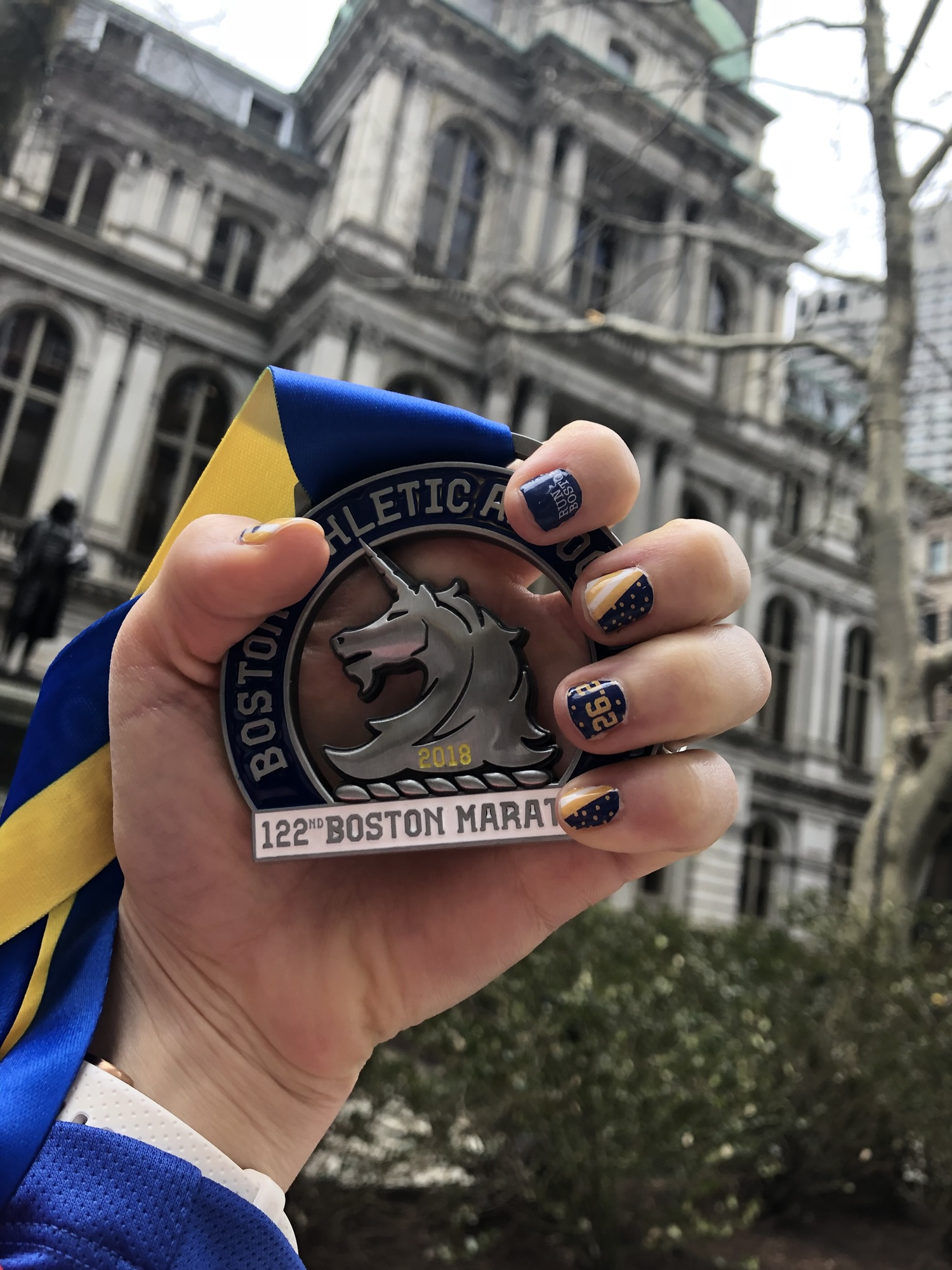 2018 Boston Marathon finisher medal held after completing one of the toughest Boston Marathons in history.