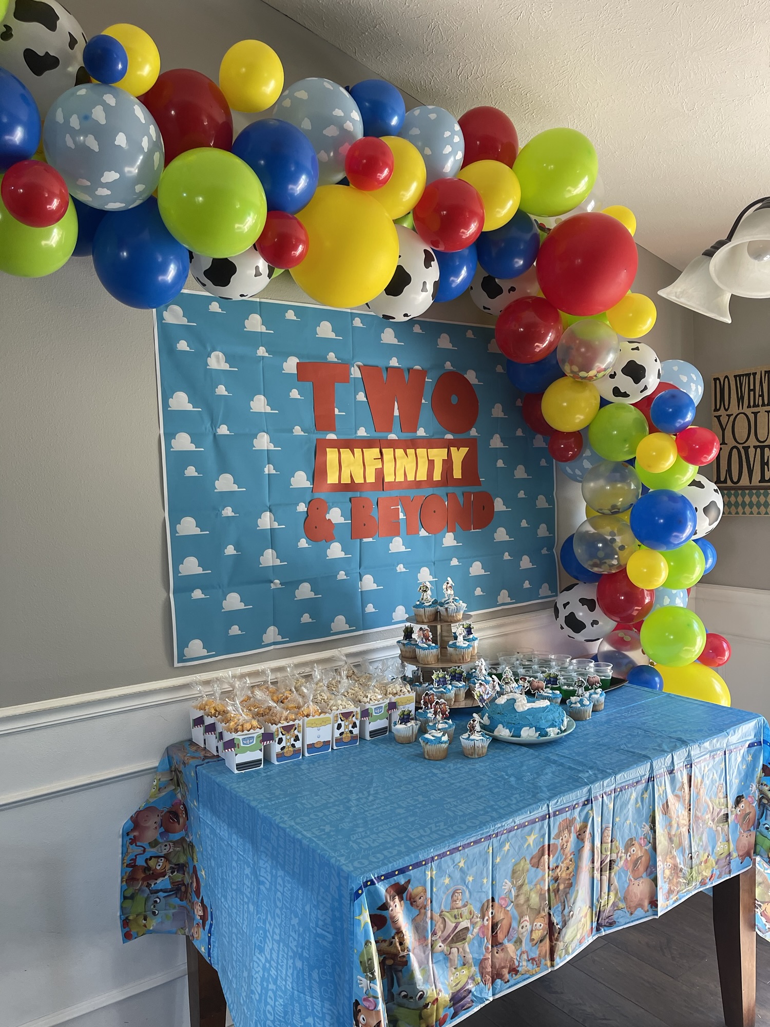 DIY Toy Story birthday party decorations with a Two Infinity and Beyond backdrop, balloon garland, and themed dessert table.