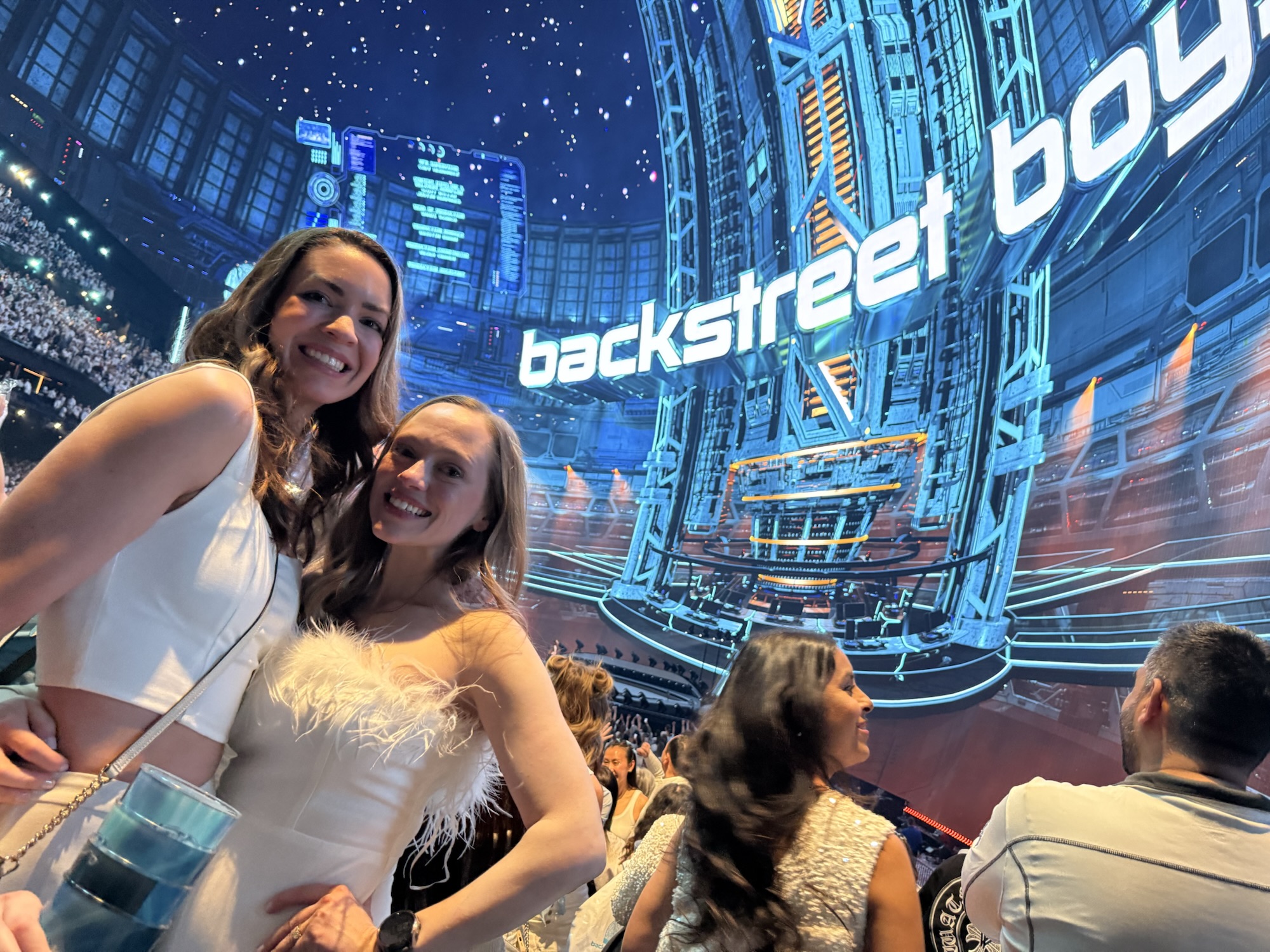 Two women wearing coordinated all-white outfits at the Backstreet Boys concert at the Sphere in Las Vegas.