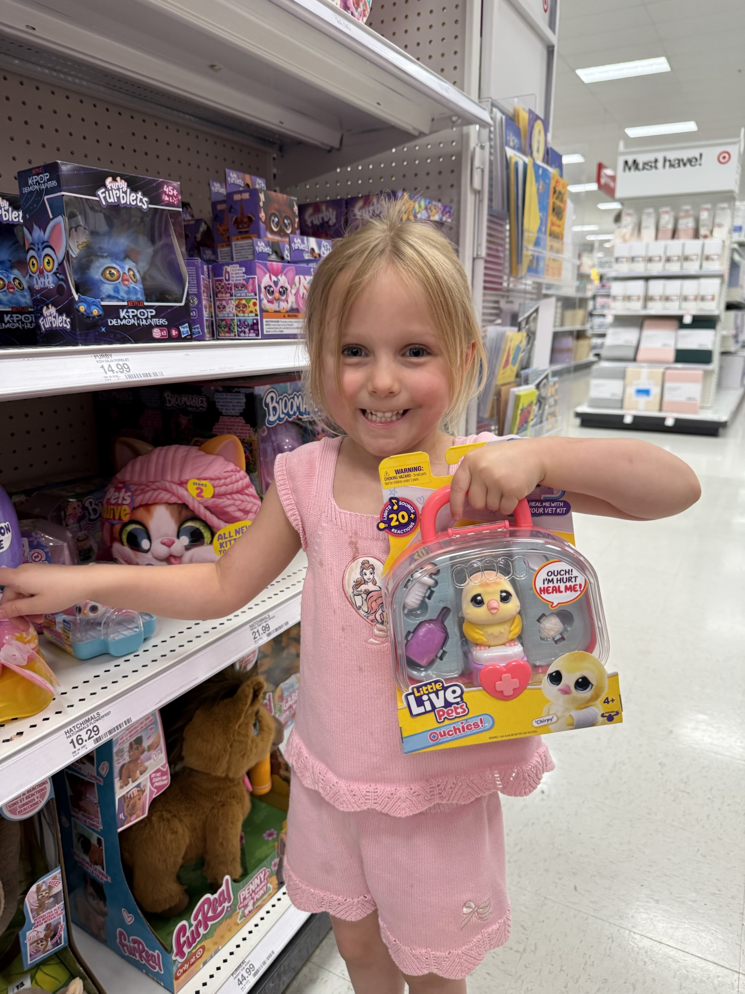 Young girl in a toy store holding up a toy she wants to photograph and send to Santa for her Christmas wishlist.